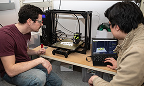 Engineering students work with a 3D printer