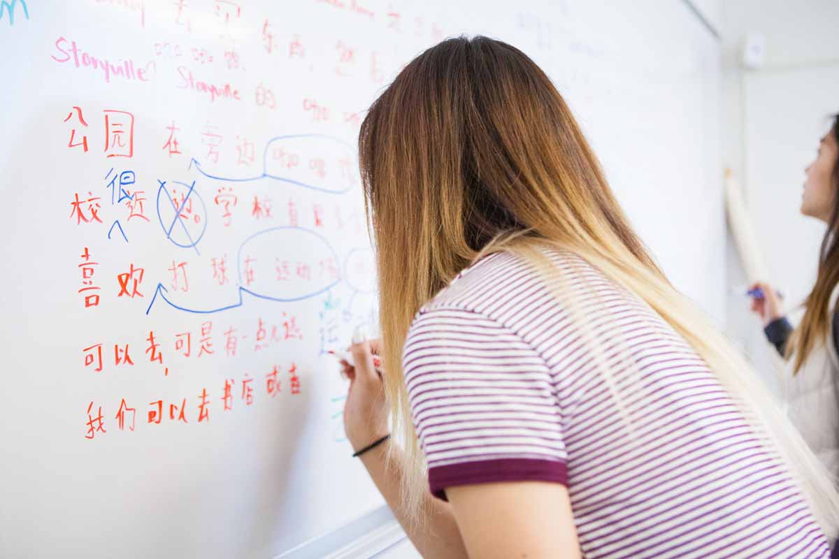 Students writing Mandarin on a white board