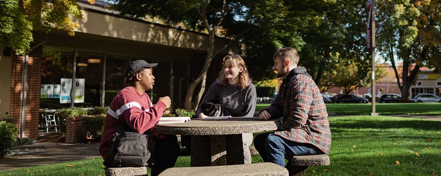 Students talk around a table in Tiffany Loop outside of the Student Union Building