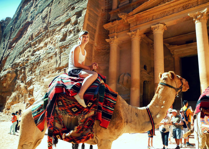 a girl rides a camel in petra, jordan