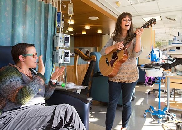 An SPU student plays the guitar for a hospital patient