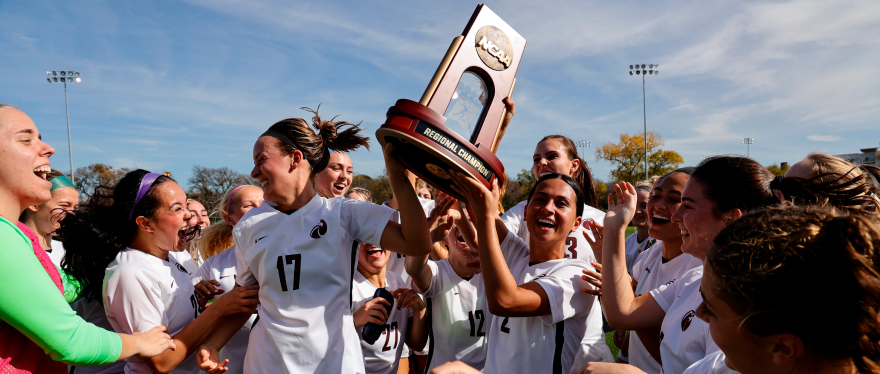 Makena Rietz (17) and Madison Ibale (2) celebrate with teammates by hoisting the NCAA Division II West Region women’s soccer championship trophy.