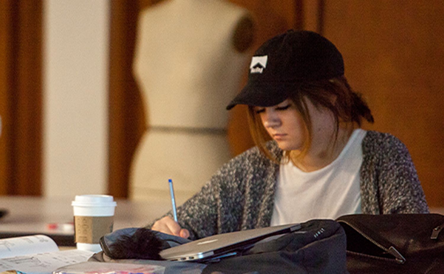 A female SPU student at a table with a design mannequin behind her in an apparel design lab