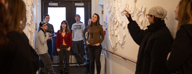 Students  and professor in hallway with whiteboards.