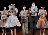 Several SPU student actors in costume holding a newspaper and wearing a white mask