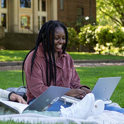 An SPU student works on her laptop in Tiffany Loop