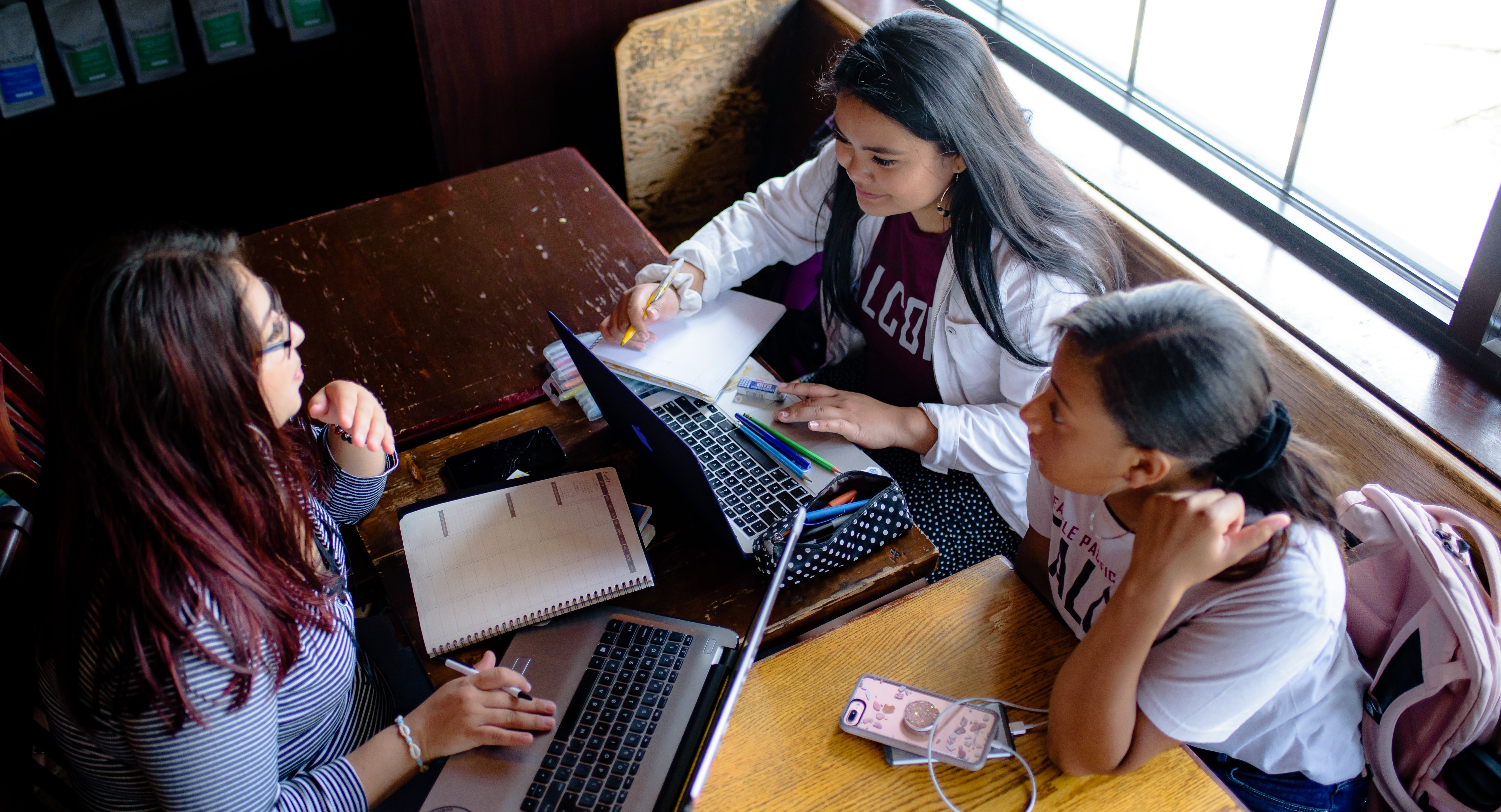 Three students study together at a cafe table