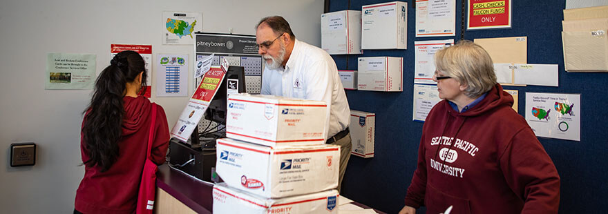 SPU Mailing Services staff help a student mail a package