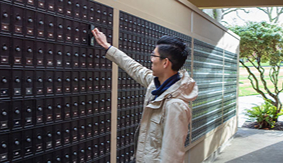 A male SPU student accessing his mailbox outside of the Student Union Building