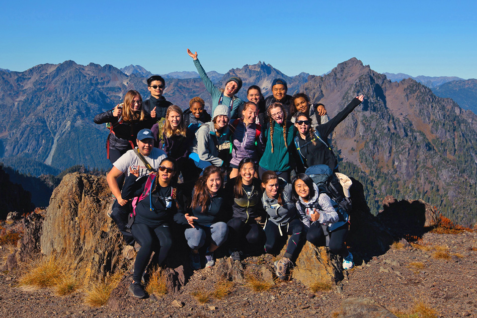 More than a dozen SPU students in the Outdoor Club have gathered on a mountain overlook 