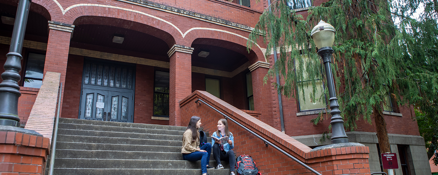 Two graduate School of Education students talk on the steps of Peterson Hall