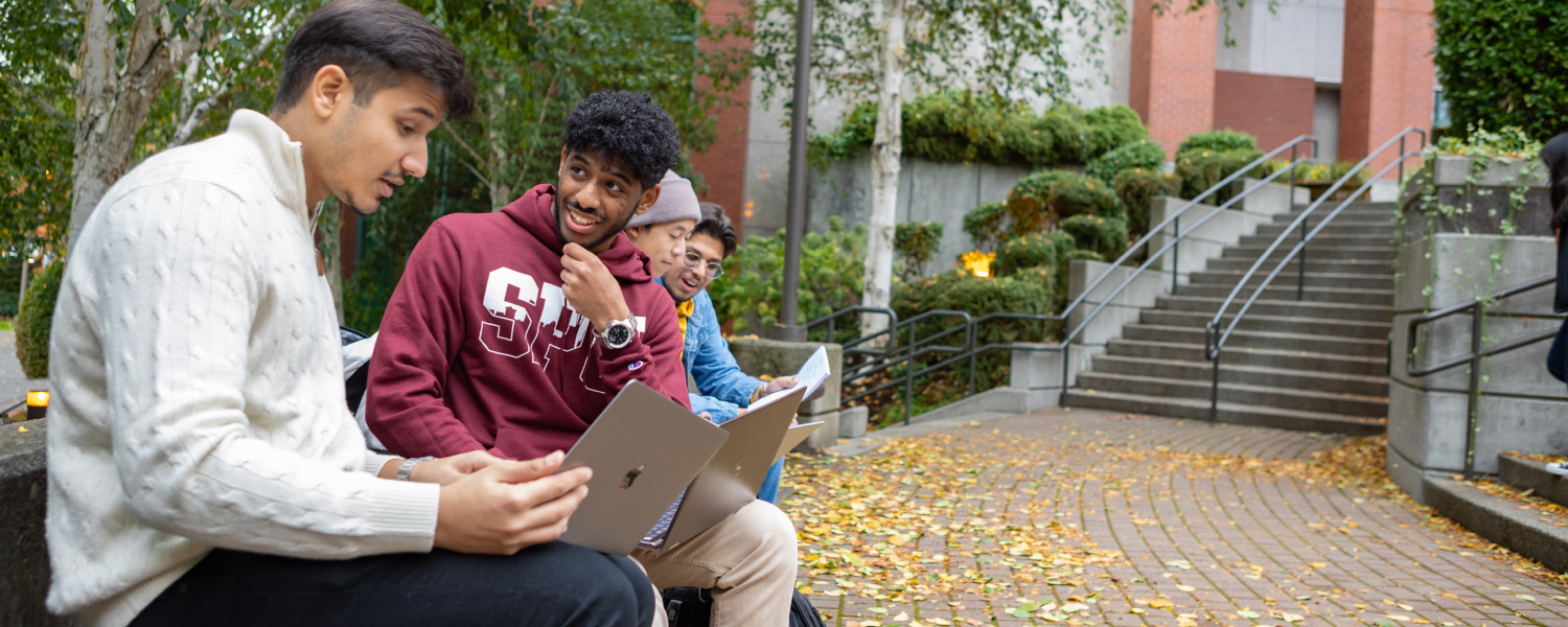 Four students interact near Martin Square on the SPU campus in the autumn.