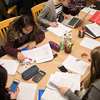 SPU students gather around a desk, studying hard for finals