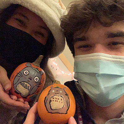 Two SPU students hold up pumpkins painted with Totoro