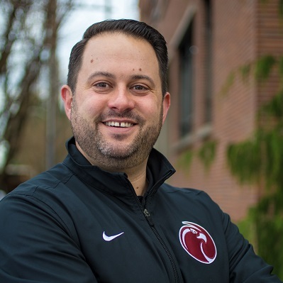 SPU athletic director, Jackson Stava, standing on the SPU campus with his arms crossed