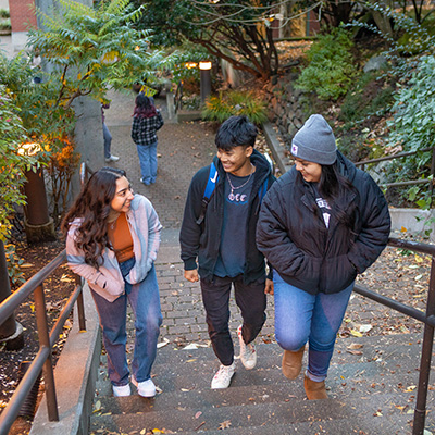 Three SPU students walk up a long exterior stairway on campus