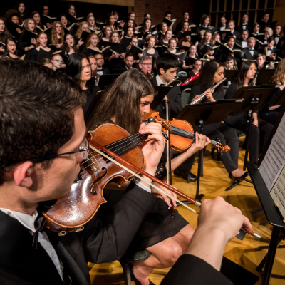 SPU student musicians perform onstage, with violinists in the foreground of the picture