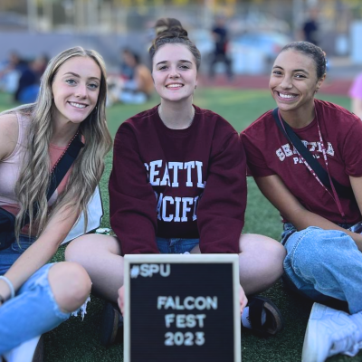 three female students by sign reading falcon fest 2023