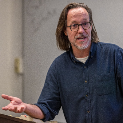 A closeup of Professor David Nienhaus as he talks to his classroom
