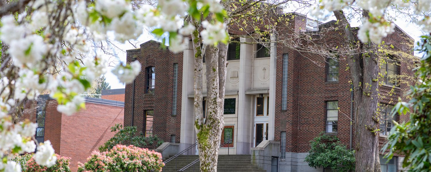 McKinley Hall on the SPU campus as seen beyond spring foliage 