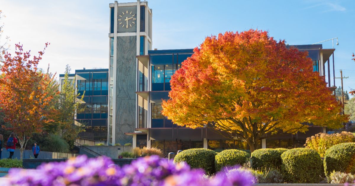 Demaray Hall on the Seattle Pacific University campus in the fall, with a blue sky above and trees filled with autumn color in front