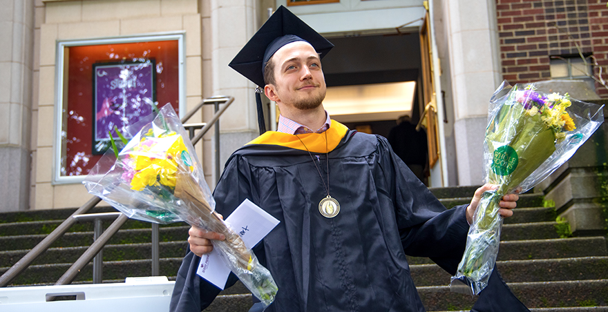 A student walking out of McKinley Hall after receiving his hood at SPU's graduate hooding ceremony