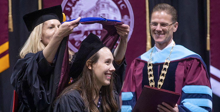An SPU graduate student receives her hood during the 2019 Graduate Hooding ceremony - photo by Dan Sheehan