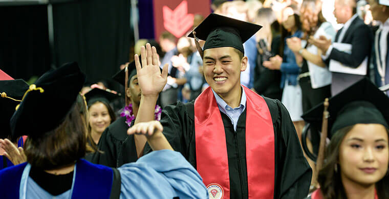 An SPU student high-fives a professor at the 2019 Undergraduate Commencement ceremony