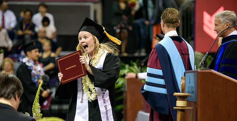 An SPU graduate holds up her diploma at the 2019 Undergraduate Commencement ceremony