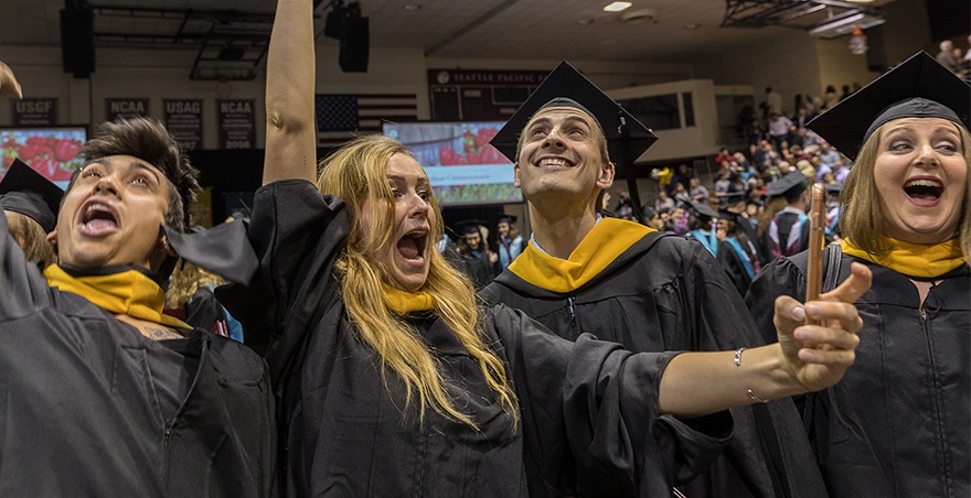 Four master's degree recipients cheer loudly as they celebrate their graduate at the SPU Graduate Commencement Ceremony.