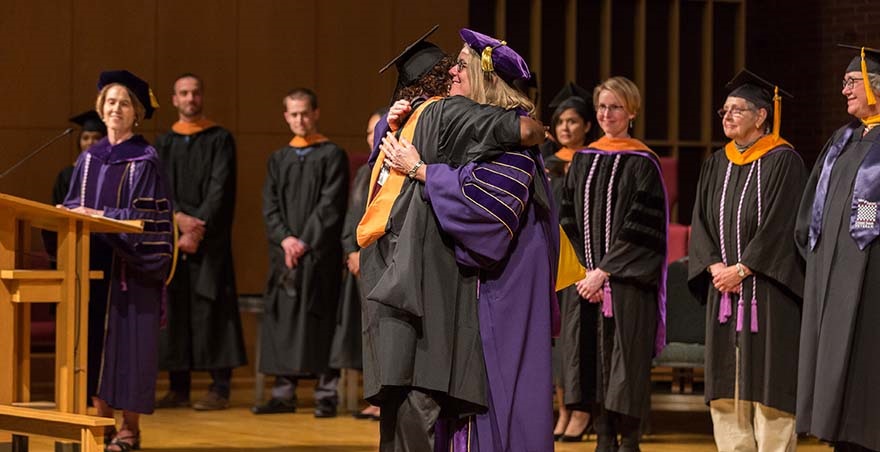 A DNP recipient being hugged upon her graduation by the dean of the School of Health Sciences.