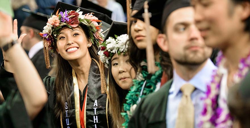 Several SPU undergraduate students, including two wearing wreaths of flowers on their heads, gather at the Undergraduate Commencement Ceremony.