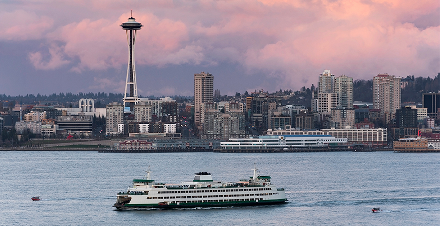 A ferry on Puget Sound with a view of the Seattle Space Needle and beautiful sunset.