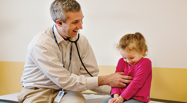 Dr. Christopher Jones listens to the heartbeat of a giggling patient.