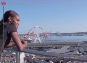 A student looking out on Elliot Bay with the Seattle Great Wheel in the background