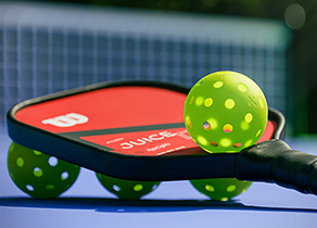 Pickleball paddle and balls on a court | photo by Brendan Sapp